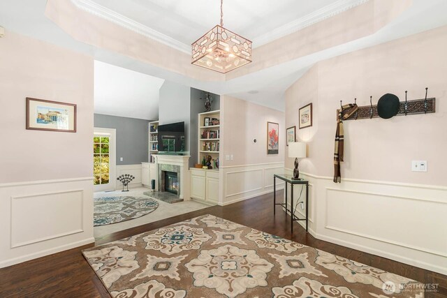 2444 220th Pl NE, Sammamish, WA 98074 - foyer entrance featuring wood finished floors, a chandelier, a high end fireplace, a wainscoted wall, and crown molding