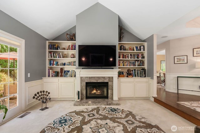 2444 220th Pl NE, Sammamish, WA 98074 - living room featuring lofted ceiling, light colored carpet, wainscoting, a premium fireplace, and built in shelves