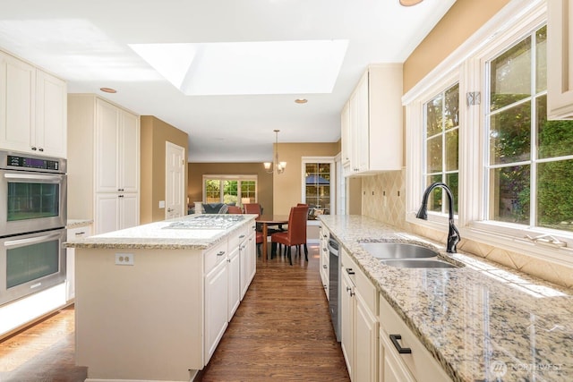 2444 220th Pl NE, Sammamish, WA 98074 - kitchen with stainless steel appliances, a skylight, a center island, dark wood-type flooring, and light stone countertops