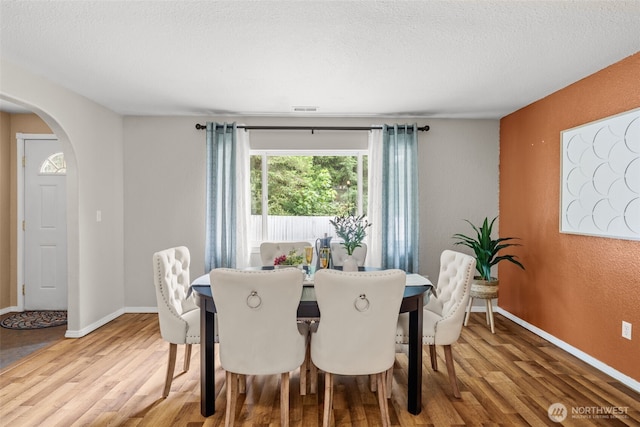 19221 Patterson Rd E, Orting, WA 98360 - dining area with arched walkways, wood finished floors, and a textured ceiling