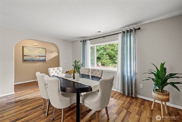 19221 Patterson Rd E, Orting, WA 98360 - dining area with wood finished floors, arched walkways, a textured wall, and a textured ceiling