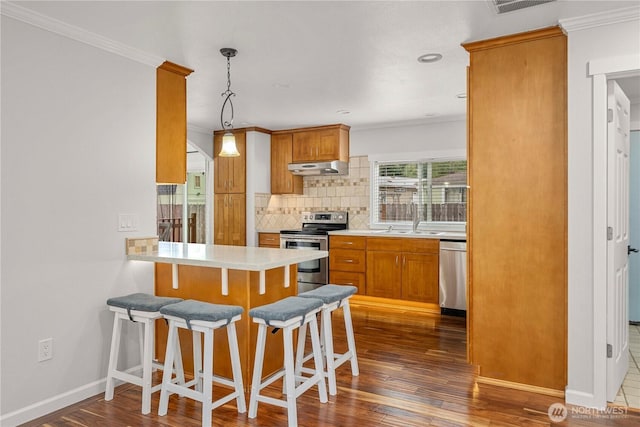 4248 A St SE Unit 423, Auburn, WA 98002 - kitchen featuring appliances with stainless steel finishes, under cabinet range hood, crown molding, decorative backsplash, and dark wood finished floors