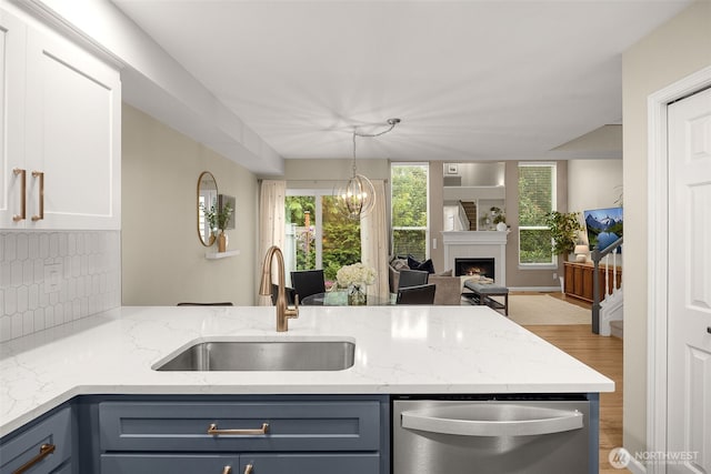 23501 112th Ave SE Unit F103, Kent, WA 98031 - kitchen with dishwasher, a peninsula, light wood-style flooring, backsplash, and light stone countertops