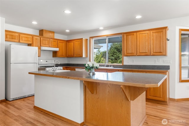 7104 84th St E, Puyallup, WA 98371 - kitchen featuring white appliances, a center island with sink, dark countertops, light wood finished floors, and recessed lighting