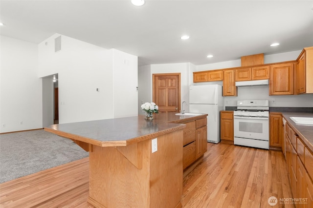 7104 84th St E, Puyallup, WA 98371 - kitchen with white appliances, under cabinet range hood, light wood-type flooring, an island with sink, and recessed lighting