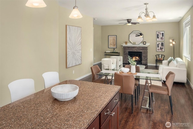 15230 Kayla St SE, Yelm, WA 98597 - dining room featuring a ceiling fan, dark wood-style flooring, a stone fireplace, and a chandelier