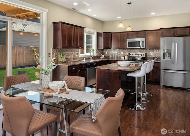 15230 Kayla St SE, Yelm, WA 98597 - kitchen featuring appliances with stainless steel finishes, dark brown cabinetry, decorative backsplash, a kitchen island, and recessed lighting