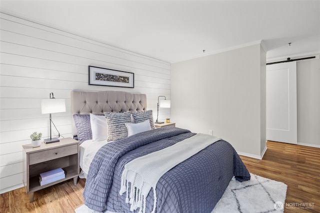 12618 109th Ct NE Unit H102, Kirkland, WA 98034 - bedroom featuring a barn door, wood finished floors, ornamental molding, and wooden walls