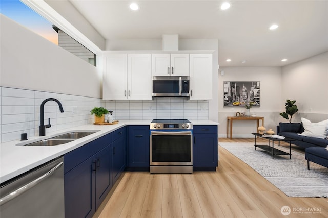 9692 51st Ave S, Seattle, WA 98118 - kitchen featuring stainless steel appliances, blue cabinetry, light countertops, white cabinetry, and recessed lighting