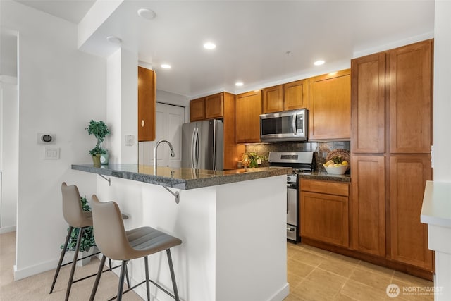 2607 Western Ave Unit 655, Seattle, WA 98121 - kitchen featuring stainless steel appliances, a kitchen bar, recessed lighting, brown cabinetry, and a peninsula