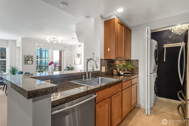 2607 Western Ave Unit 655, Seattle, WA 98121 - kitchen with stainless steel dishwasher, stacked washer / drying machine, a peninsula, tile countertops, and brown cabinetry