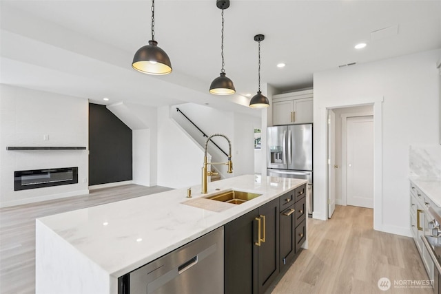 3102 44th Ave NE, Tacoma, WA 98422 - kitchen with appliances with stainless steel finishes, light wood-style flooring, pendant lighting, a center island with sink, and light stone counters