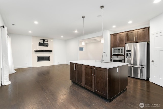 4214 223rd Pl SE, Bothell, WA 98021 - kitchen featuring stainless steel appliances, dark brown cabinets, dark wood-style flooring, a large fireplace, and recessed lighting