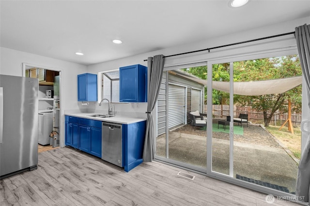 900 Dundee Rd NW, Olympia, WA 98502 - kitchen featuring appliances with stainless steel finishes, blue cabinetry, washer / dryer, light countertops, and light wood finished floors