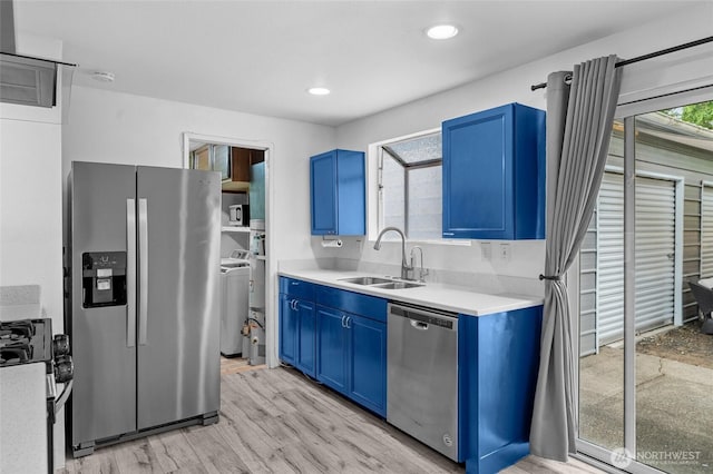 900 Dundee Rd NW, Olympia, WA 98502 - kitchen with stainless steel appliances, blue cabinetry, light countertops, washer / clothes dryer, and light wood-type flooring