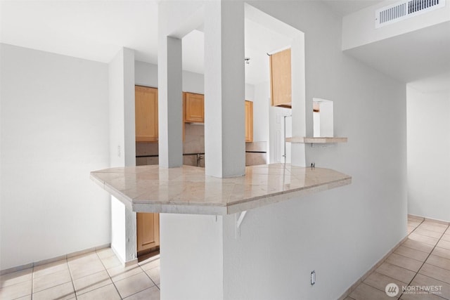 14510 124th Ave NE Unit H79, Kirkland, WA 98034 - kitchen featuring a peninsula, light tile patterned floors, a breakfast bar area, and tile counters