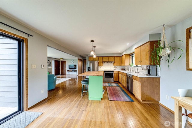 1121 W 12th St, Port Angeles, WA 98363 - kitchen featuring stainless steel appliances, light wood-type flooring, decorative backsplash, a kitchen bar, and butcher block counters