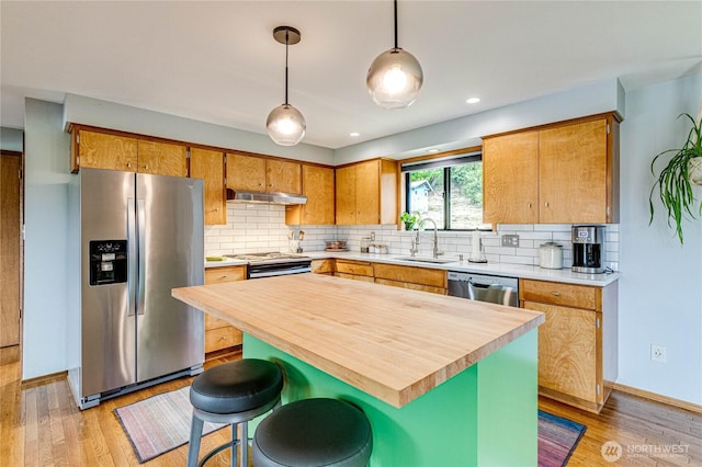 1121 W 12th St, Port Angeles, WA 98363 - kitchen with appliances with stainless steel finishes, under cabinet range hood, light wood-type flooring, tasteful backsplash, and recessed lighting