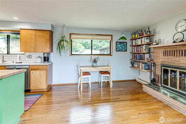 1121 W 12th St, Port Angeles, WA 98363 - kitchen with dishwasher, a baseboard radiator, light wood finished floors, a fireplace, and decorative backsplash