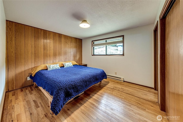 1121 W 12th St, Port Angeles, WA 98363 - bedroom featuring a baseboard heating unit, light wood-style flooring, a closet, and a textured ceiling