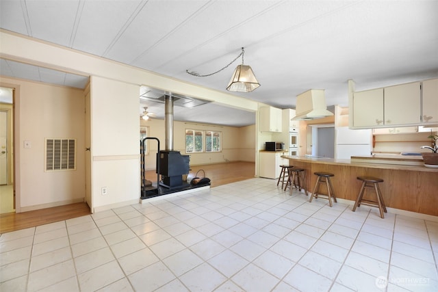 15932 427th Ave SE, Gold Bar, WA 98251 - kitchen featuring white appliances, custom exhaust hood, a wood stove, a kitchen breakfast bar, and a peninsula