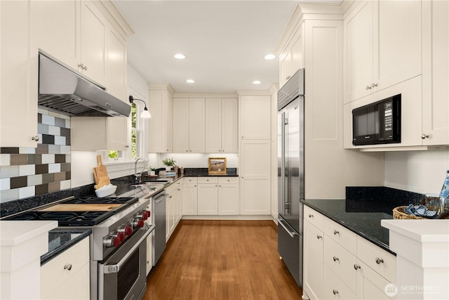 1515 2nd Ave W, Seattle, WA 98119 - kitchen with high quality appliances, under cabinet range hood, light wood-style flooring, white cabinets, and recessed lighting