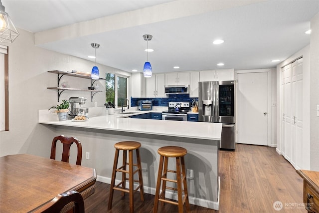 19833 95th Ave NE, Bothell, WA 98011 - kitchen featuring appliances with stainless steel finishes, a peninsula, light countertops, wood finished floors, and a breakfast bar area