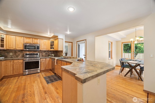 3120 Tanglewood Ln, Bellingham, WA 98226 - kitchen featuring appliances with stainless steel finishes, a peninsula, light wood finished floors, decorative backsplash, and lofted ceiling