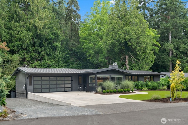 23406 Humber Ln, Edmonds, WA 98020 - view of front of house featuring driveway, a garage, a chimney, a metal roof, and a standing seam roof