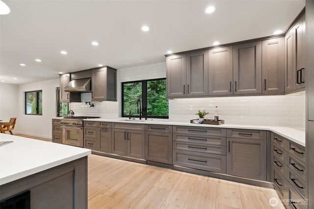 23406 Humber Ln, Edmonds, WA 98020 - kitchen featuring high end stainless steel range, wall chimney range hood, light wood-style floors, recessed lighting, and backsplash