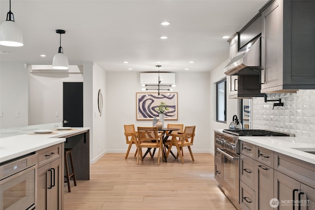 23406 Humber Ln, Edmonds, WA 98020 - kitchen featuring stainless steel stove, under cabinet range hood, light wood-style flooring, tasteful backsplash, and a wall mounted AC