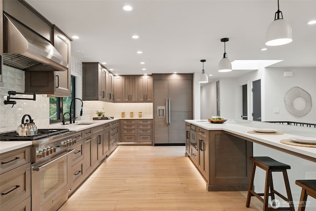 23406 Humber Ln, Edmonds, WA 98020 - kitchen featuring built in appliances, wall chimney exhaust hood, light countertops, backsplash, and light wood-style floors