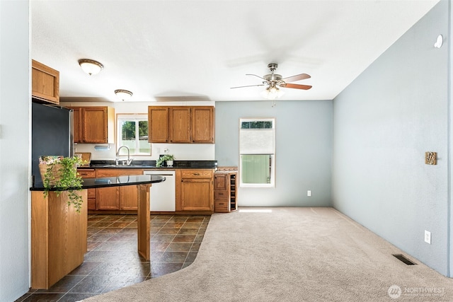 10900 Kuhlmann Rd SE Unit 50, Olympia, WA 98513 - kitchen with dishwasher, dark countertops, brown cabinets, and ceiling fan