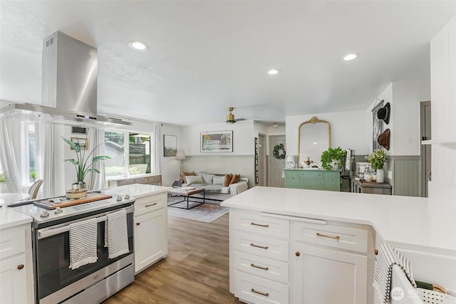 15922 Lindsay Rd SE, Yelm, WA 98597 - kitchen with electric stove, island exhaust hood, light wood-style floors, white cabinetry, and light countertops