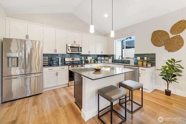 5738 S Zabo Rd, Spokane, WA 99224 - kitchen with appliances with stainless steel finishes, dark countertops, light wood-style floors, white cabinetry, and vaulted ceiling