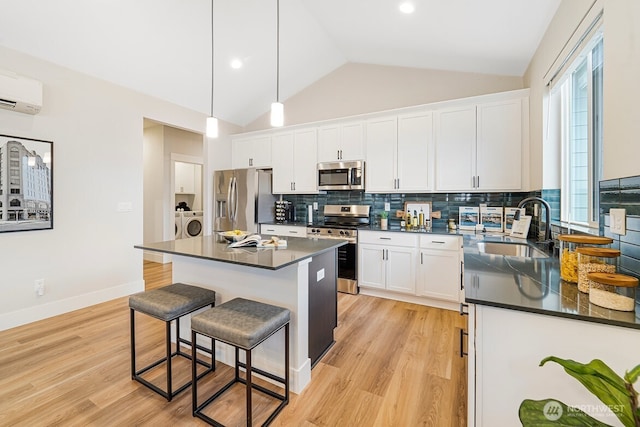 5738 S Zabo Rd, Spokane, WA 99224 - kitchen with appliances with stainless steel finishes, washing machine and clothes dryer, dark countertops, a kitchen breakfast bar, and an AC wall unit