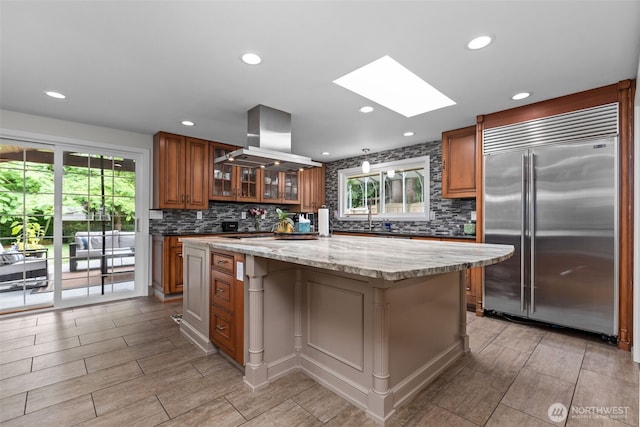 4709 144th St E, Tacoma, WA 98446 - kitchen featuring stainless steel built in fridge, brown cabinets, a skylight, island exhaust hood, and healthy amount of natural light