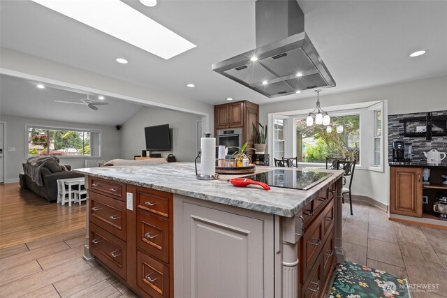 4709 144th St E, Tacoma, WA 98446 - kitchen with island range hood, open floor plan, light wood-style floors, light stone counters, and vaulted ceiling