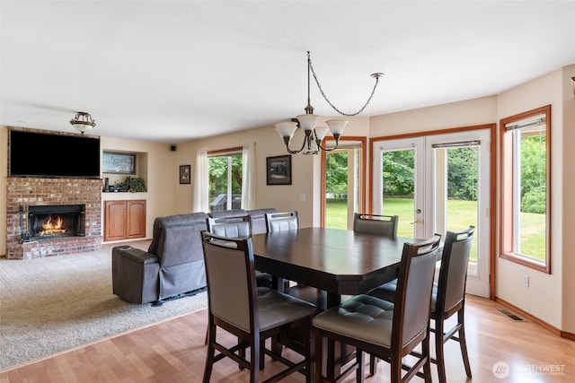 3517 Frogs Leap Ln NE, Olympia, WA 98506 - dining space with light wood-style flooring, a brick fireplace, and a chandelier