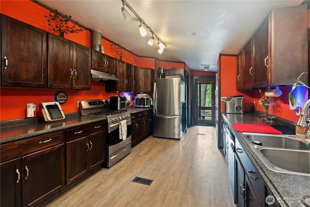 5818 Everson Goshen, Bellingham, WA 98226 - kitchen featuring appliances with stainless steel finishes, under cabinet range hood, dark countertops, light wood finished floors, and dark brown cabinets