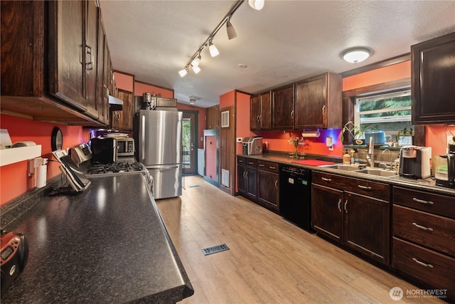 5818 Everson Goshen, Bellingham, WA 98226 - kitchen featuring appliances with stainless steel finishes, dark brown cabinetry, light wood finished floors, dark countertops, and under cabinet range hood