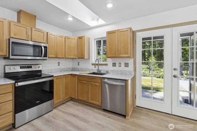 17701 Vine Ln SE, Yelm, WA 98597 - kitchen featuring appliances with stainless steel finishes, light countertops, french doors, light wood-style flooring, and a skylight