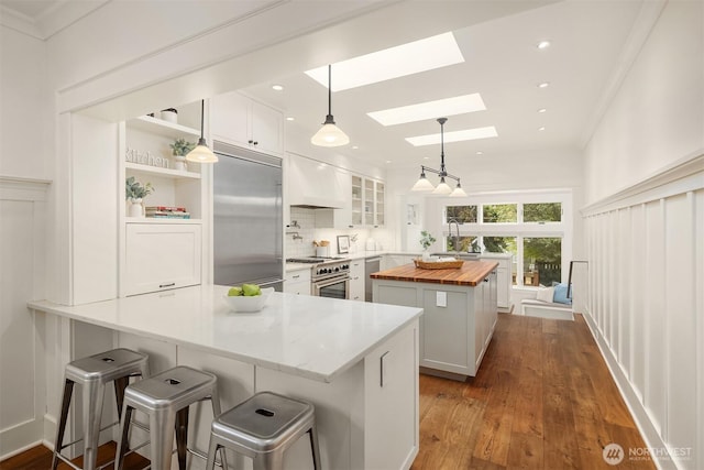 5526 34th Ave NE, Seattle, WA 98105 - kitchen featuring butcher block countertops, high end appliances, a skylight, a peninsula, and white cabinets