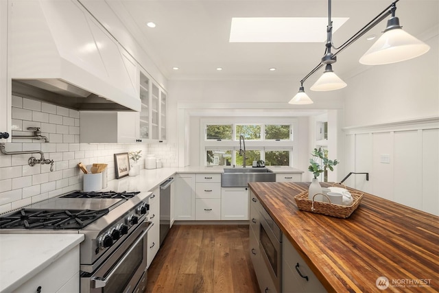5526 34th Ave NE, Seattle, WA 98105 - kitchen featuring butcher block counters, stainless steel appliances, custom exhaust hood, white cabinetry, and glass insert cabinets