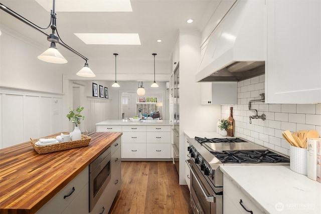 5526 34th Ave NE, Seattle, WA 98105 - kitchen with butcher block countertops, appliances with stainless steel finishes, custom exhaust hood, a skylight, and white cabinetry