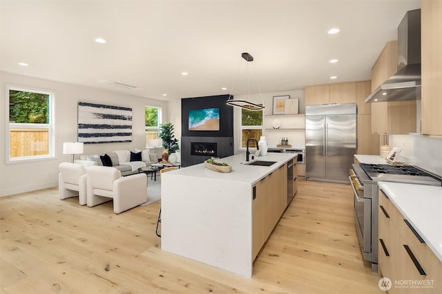 819 18th Ave W, Kirkland, WA 98033 - kitchen with high quality appliances, wall chimney exhaust hood, light brown cabinets, modern cabinets, and light wood-type flooring
