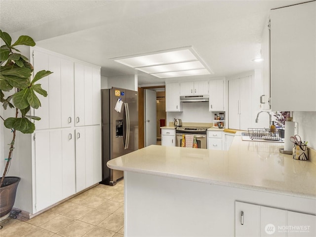6908 254th St E, Graham, WA 98338 - kitchen featuring appliances with stainless steel finishes, under cabinet range hood, a peninsula, light tile patterned floors, and white cabinets