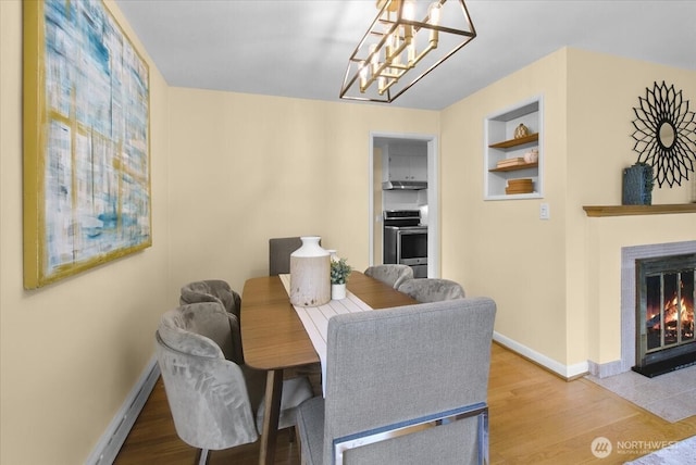 9237 24th Ave NW, Seattle, WA 98117 - dining area with wood finished floors, a fireplace with flush hearth, a chandelier, and built in features