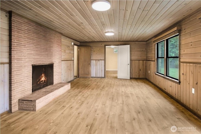 9237 24th Ave NW, Seattle, WA 98117 - unfurnished living room with wood walls, light wood finished floors, wooden ceiling, and a brick fireplace