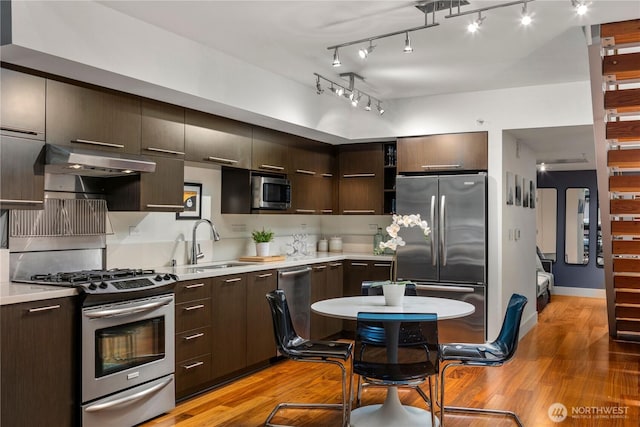 2911 2nd Ave Unit 120, Seattle, WA 98121 - kitchen featuring stainless steel appliances, light wood-style flooring, under cabinet range hood, light countertops, and dark brown cabinets